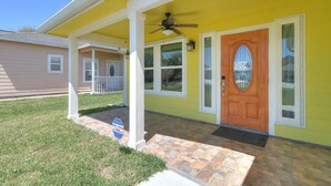 A yellow house with a wooden door, a porch, and a small window. - A Wave From It All 3 Bedroom Home by RedAwning (Rockport)