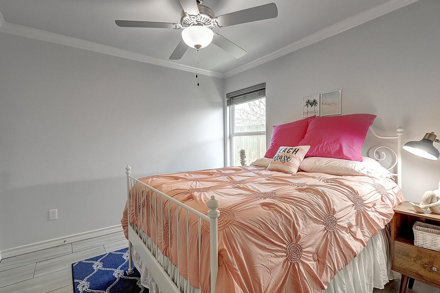 Quarto com uma cama, ventilador de teto, janela e mesa de cabeceira.