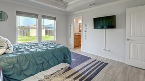 A bedroom with a bed, a ceiling fan, a TV, and a view of the backyard. - A Wave From It All 3 Bedroom Home by RedAwning (Rockport)