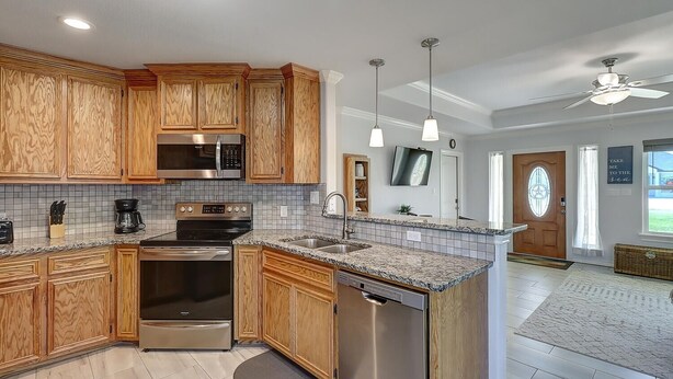 A modern kitchen with wooden cabinets, stainless steel appliances, and a granite countertop. - A Wave From It All 3 Bedroom Home by RedAwning (Rockport)