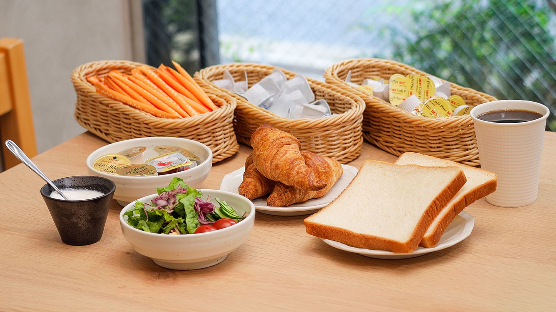 A table with food items including bread, croissants, a salad, soup, and a cup of coffee.