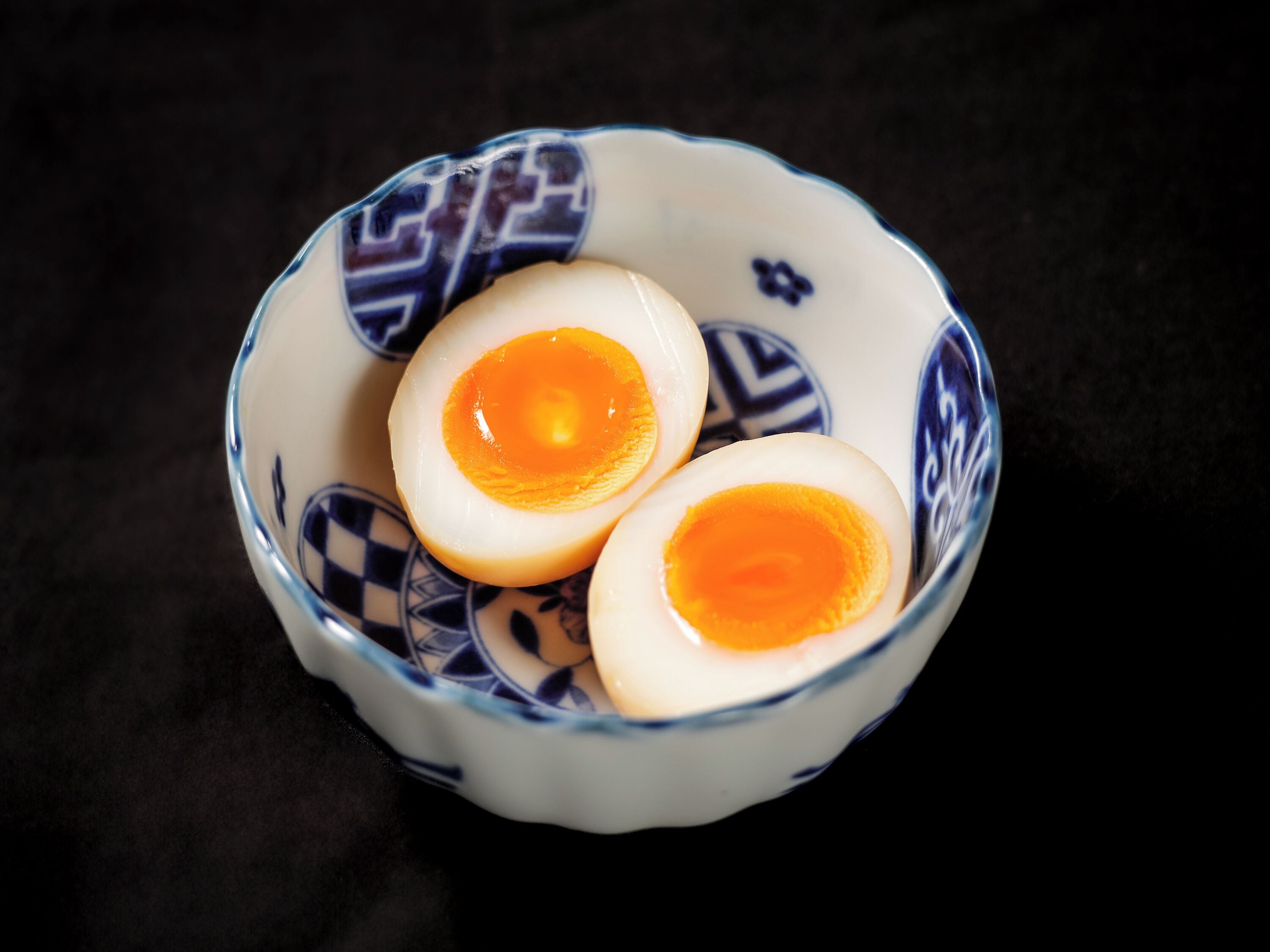 A bowl with two halves of a boiled egg.