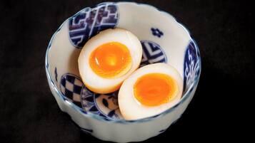 A bowl with two halves of a boiled egg.
