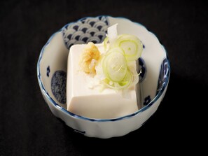 A bowl with a white substance, possibly tofu, garnished with green onions and shredded white material, possibly daikon radish, on a dark surface. - APA Hotel Asakusa Shin Okachimachi Ekimae (Tokyo)
