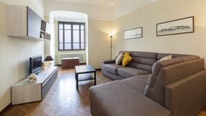 Uma sala de estar moderna com um sofá, uma televisão e um candeeiro.