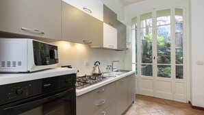 Cozinha moderna com micro-ondas, fogão e forno embutidos. Grande janela com vista para o verde lá fora.