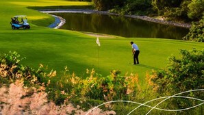 A golf course with a pond, a golf cart, and a golfer. - Aquiraz Manhattan Riviera (Aquiraz)