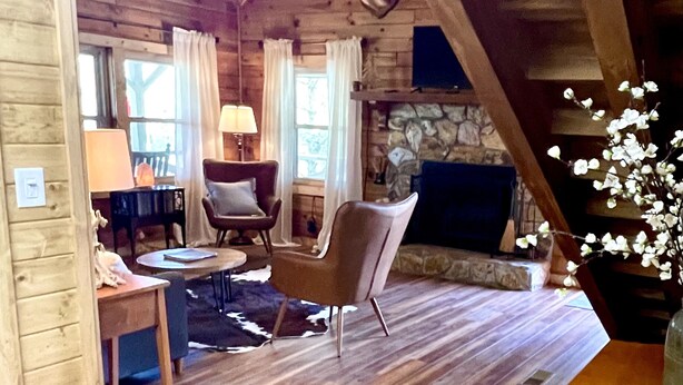 L’intérieur d’un chalet confortable, avec une cheminée, des meubles en bois et un mur en pierre.