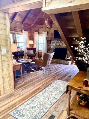 L’intérieur d’un chalet chaleureux, avec une cheminée, des meubles en bois et un mur en pierre.