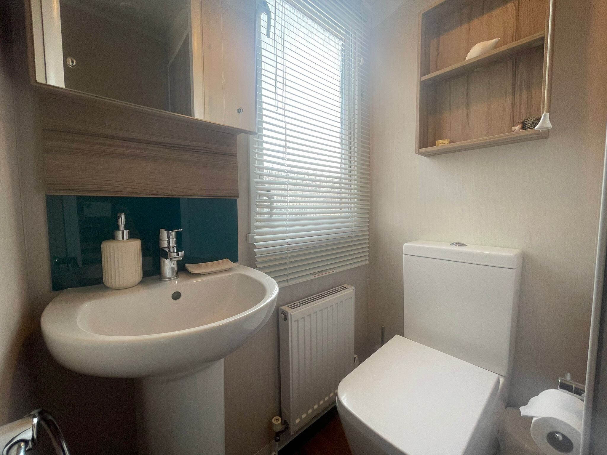 A compact bathroom with a white sink, toilet, and radiator.