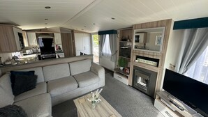 Ein kompaktes Wohnmobil-Interieur mit Küchenzeile, einer Sitzecke, einem Couchtisch und einem Fernsehbereich.