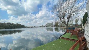 Un entorno tranquilo junto al lago, con una terraza de madera y zona de estar.