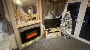 Una sala de estar con chimenea, televisor y árbol de Navidad.