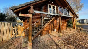 A wooden log cabin with a sign reading "Woodpecker Lodge."