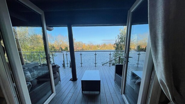 A deck with a view of a lake, outdoor furniture, and a railing.