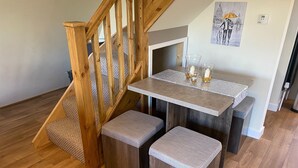 A wooden staircase leading to a room with a table and bench.