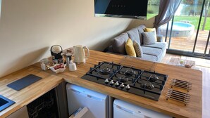 A modern kitchen with a gas stove, Bosch dishwasher, and a flat-screen TV mounted above the counter.