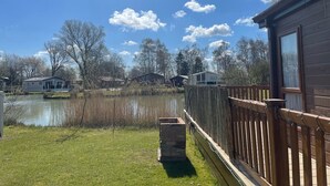 Järvenrantatontti, jossa on puinen terassi, kivinen kukka-astia ja näkymä järvelle sekä ympäröiville puille.