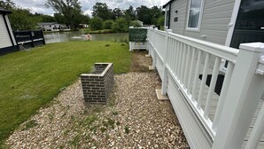 A residential property with a grassy yard, a brick structure, and a white fence. - Luxury lakeside lodge with sunken hot tub prime location on bull rush lake @tattershall lakes (Tattershall)