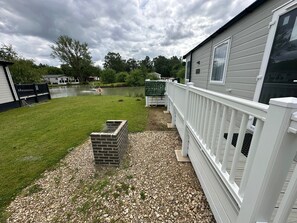 A residential property with a grassy yard, a brick structure, and a white fence. - Luxury lakeside lodge with sunken hot tub prime location on bull rush lake @tattershall lakes (Tattershall)