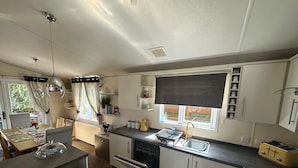 Eine kleine Küche mit integriertem Geschirrspüler, einem Gasherd und einem Fenster mit Blick ins Freie.