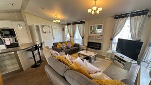Ein modernes Wohnzimmer mit Sofa, Couchtisch, Fernseher, Kamin und Küchenzeile.