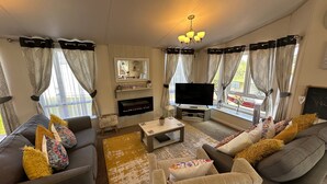 Ein Wohnzimmer mit grauen Sofas, einem Couchtisch, einem Flachbildfernseher und einem Kamin.