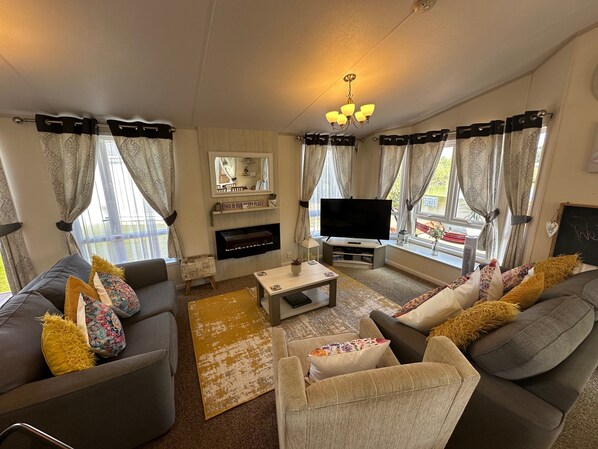 A living room with grey sofas, a coffee table, a flat-screen TV, and a fireplace.