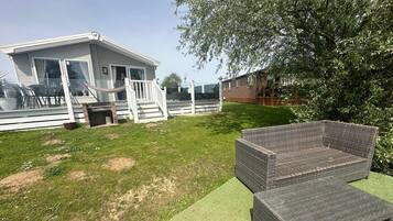 Un quartier résidentiel avec une maison blanche, une pelouse verdoyante et un ensemble de meubles en osier.