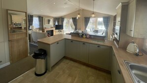 A modern kitchen with a central island, built-in microwave, and a large window with curtains.