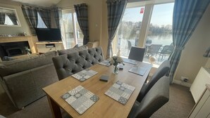 A cozy room with a sofa, a dining table with placemats, and a TV in the corner.