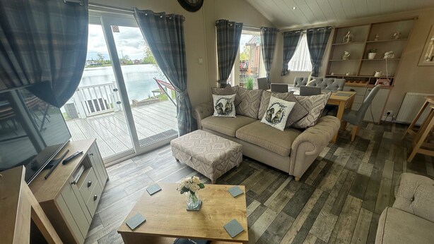 A spacious living area with a sofa, a coffee table, and a TV. There is a sliding glass door leading to an outdoor deck.
