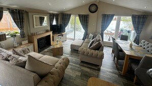 A spacious living room with a fireplace, sofas, a television, and a dining area with a table and chairs.