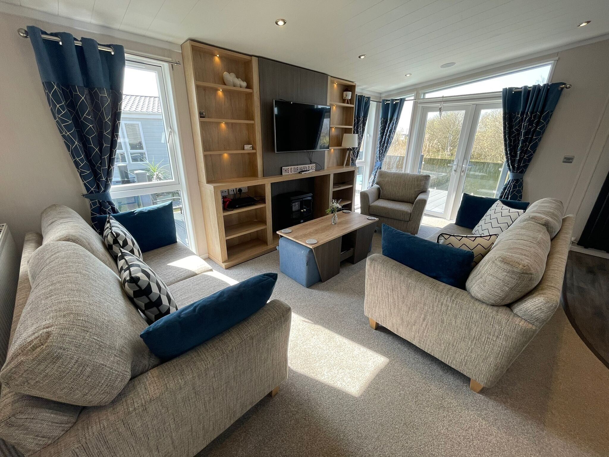 A modern living room with two sofas, a coffee table, a TV, and a built-in bookshelf.