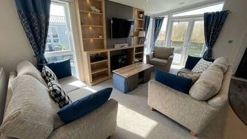 A modern living room with two sofas, a coffee table, a TV, and a built-in bookshelf.