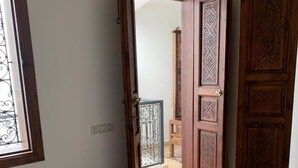 Un couloir avec une porte en bois et une fenêtre ornée de barreaux en métal.