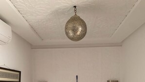 Une chambre à coucher avec un lit, un luminaire suspendu et deux lampes fixées au mur.