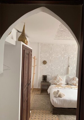 A bedroom with a bed, a wardrobe, a nightstand, and a decorative wall. - Riad Marchica MARRAKECH (Marrakech)