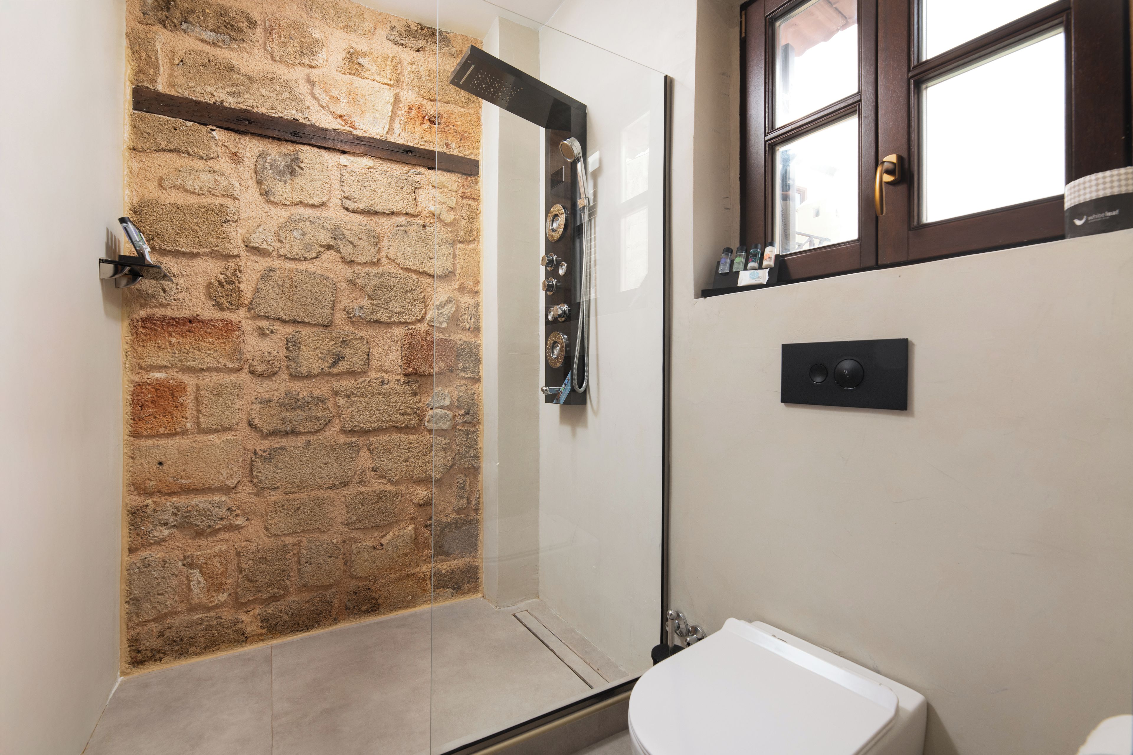 A bathroom with a shower, a toilet, and a window.