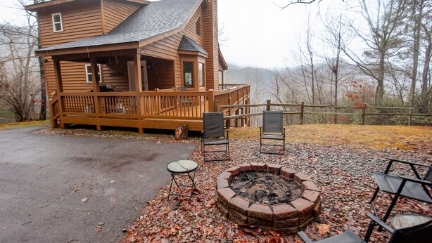 A wooden cabin with a deck, a fire pit, and outdoor seating.