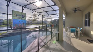 Uma área de piscina com estrutura de vidro, uma placa com o nome Extreme Getaway Homes e uma mesa com cadeiras.