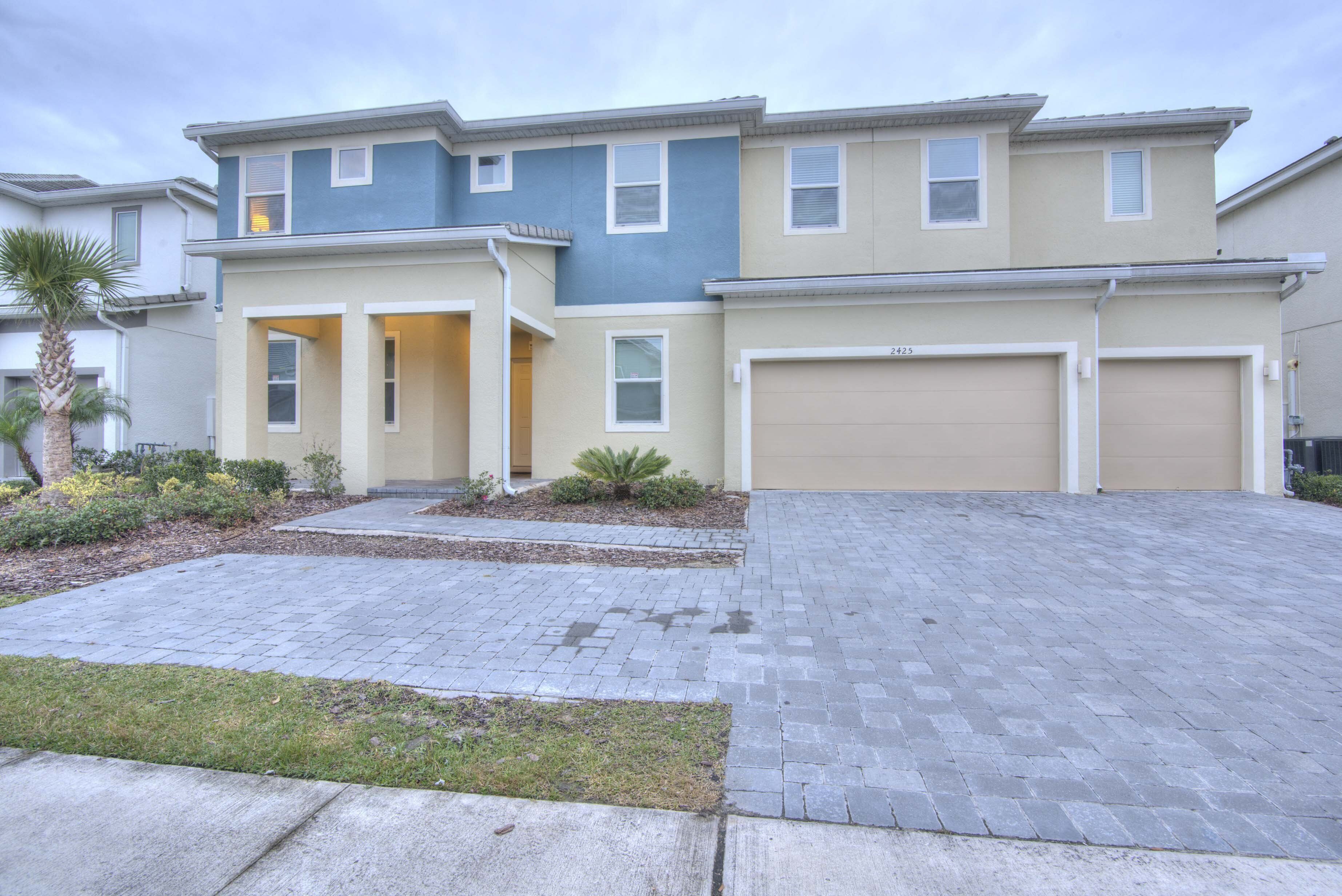 A two-story townhouse with a garage, a front entrance, and a landscaped driveway.