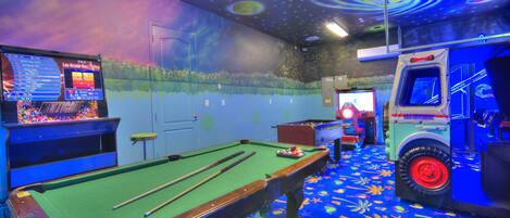 Une table de billard recouverte d’un drap vert, un queue de billard et un porte-billes.