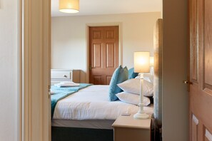 Une chambre d’hôtel avec un lit, une table de chevet, une lampe et une porte.