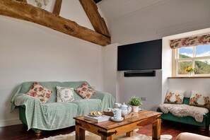 A cozy living room with a green sofa, a wooden coffee table, and a television mounted on the wall.