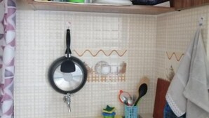 Een keuken met een spoelbak, een hangende pan en diverse keukengerei.