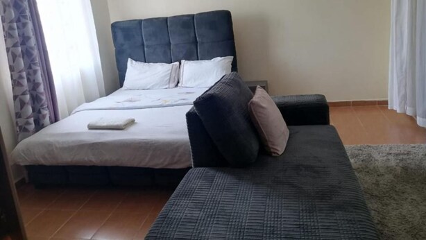 Een slaapkamer met een bed, een bank en een raam met gordijnen.