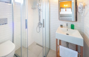 Un bagno moderno con doccia vetrata, lavandino bianco e specchio sopra, e un water.