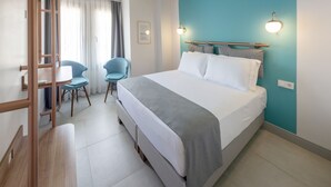 A hotel room with a bed, two chairs, a desk, and a window with curtains. - Meraki Bozcaada (Bozcaada)