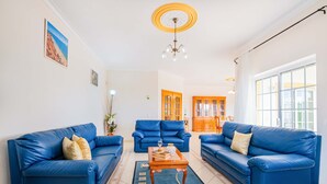 Un salon avec des canapés en cuir bleu, une table basse en bois et un lustre.